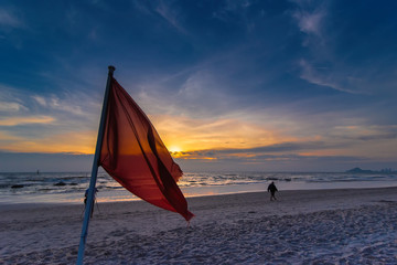 Warning sign of a red flag on the beach in the morning sunrise at Hua Hin Beach Prachuab Khirikhan, Thailand.