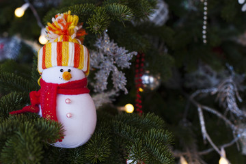 Snowman toy hanging on fir tree. xmas and new year decorations. Holidays celebration concept