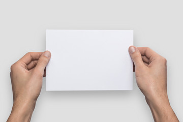 Mockup A5 letter horizontally empty blank white holds the man in his hand. Isolated on a gray background