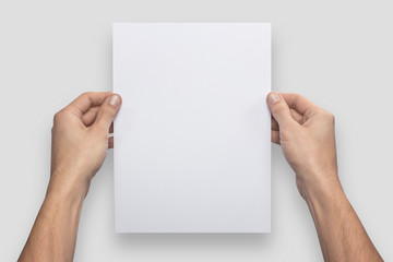 Mockup A4 letter vertical empty blank white holds the man in his hand. Isolated on a gray background