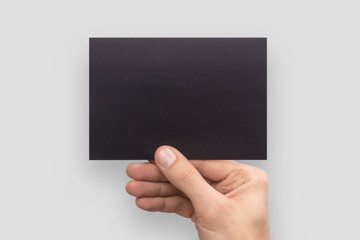 Mockup A6 empty blank black postcard horizontally holds the man in his hand in shirt. Isolated on a...