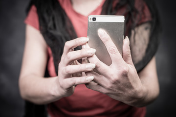 in the foreground the hands of a middle-aged woman holding the phone in front of her