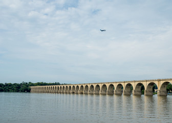 Fototapeta na wymiar Bridge over River and a Jet in the Sky