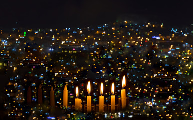 Fototapeta na wymiar Burning candles are traditional symbol for Hebrew Holidays and celebration of bright Hanukkah. Background of night sky, selective focus