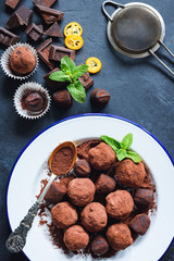 Dark chocolate truffles on white plate decorated with mint leaf