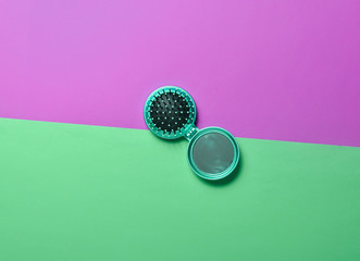 Mini mirror comb on a pink minty neon background. Top view.