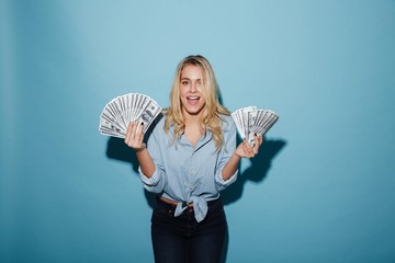 Excited young pretty blonde woman holding money in hands.