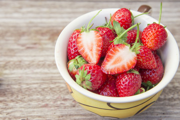 Fresh strawberries in a bowl on wooden table,Red strewberry prepatation to make Strawberry Juice.Healthy and delicious organic fruit