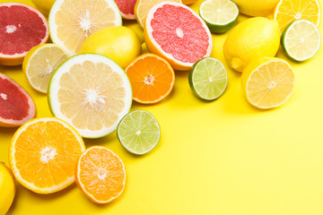 on a yellow background, lie a sliced grapefruit with other fruit lemons, and oranges