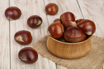 chestnut in wooden bowl on white wooden background