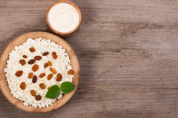 Cottage cheese in a wooden bowl on old wooden background with copy space for your text. Top view