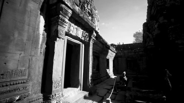 Whip pan transition movement across the interior of Banteay Srei temple with lens flares showing the ancient hindu temple structure.