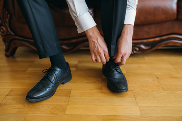 The groom sits shoes in the wedding day.