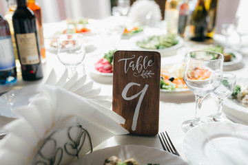 Decorated and numbered wedding table with food, drink, appliances and flowers.
