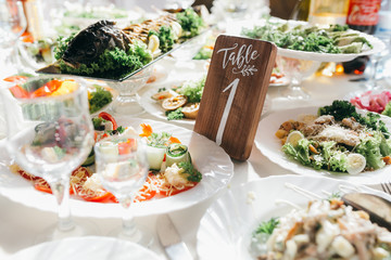 Decorated and numbered wedding table with food, drink, appliances and flowers.