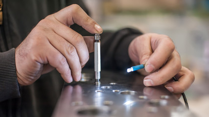 Repairman at factory screws small bolt with key. Closeup photo