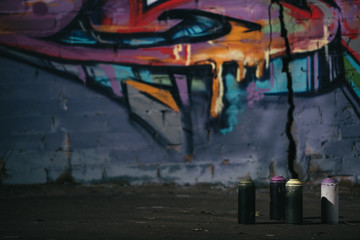 colorful graffiti on wall cans with aerosol paint standing on foreground