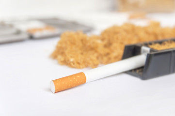 One cigarette in rolling machine like addiction from tobacco on white
