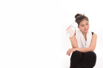 Portrait of asian woman holding bottle of water on grey background. Sport girl sit down after workout. Free from copy space.