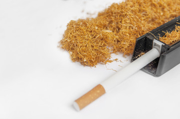 One cigarette rolling machine with addiction pile of tobacco on white