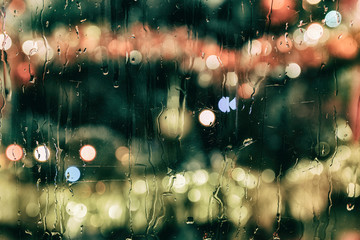 Glass covered with rain, through which you can see a Christmas tree