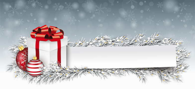 Geschenkebox mit Weihnachtskugeln, Papierzettel und Tannenzweigen im Schnee