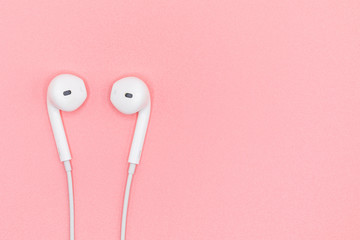 Top view Lovely Closeup of White Earphones on Pink Pastel plastic texture background. Pastel color concept, Minimal concept. Copy space. Music is my life concept. Valentine concept