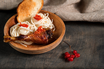  dish is grilled chicken with spaghetti and spicy tomato sauce in a wooden bowl on a dark wooden table and the background linen burlap