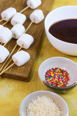 marshmallows on a sticks, laying on a chopping board. prepared for fondue.