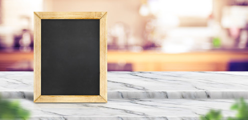 Blank blackboard on step white marble table top with blur restaurant kitchen background bokeh light...