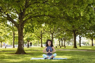 Woman performing yoga in the park - obrazy, fototapety, plakaty