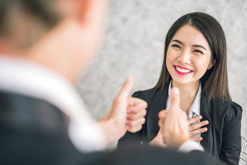 Boss/Business man employer admires young Asian business woman/staff/employee by thumb up and clap with smiling face for her success and good/best in work and recognition/appreciate.