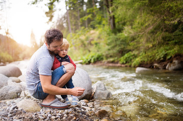 Young father with little boy at the river, summer day.
