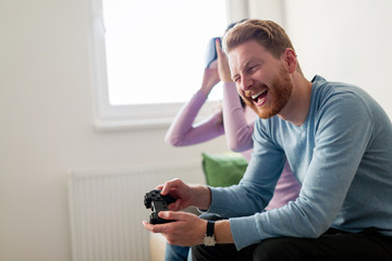 Happy young couple playing video games with virtual reality headsets