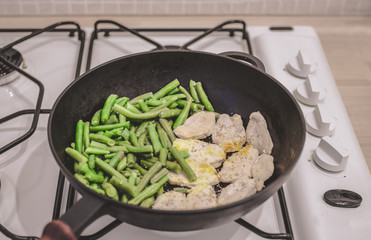 Green beans with chicken stewed on a cast-iron frying pan