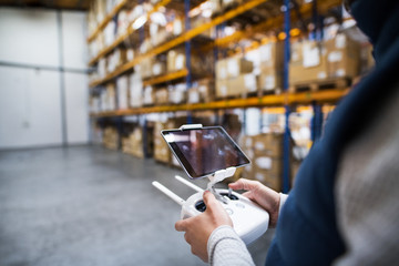 Man with tablet and drone controller in a warehouse.