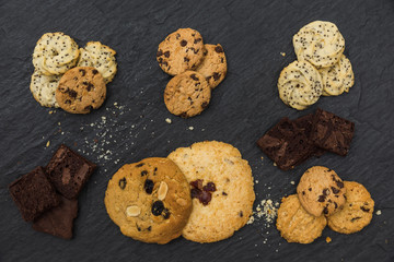 Flat lay of cookies and brownie in a row on the table top, Top view different cookies in a row on black stone background