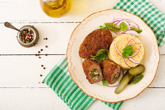 Zrazy cutlets with minced meat with pickled cucumber and eggs and garnish of bulgur