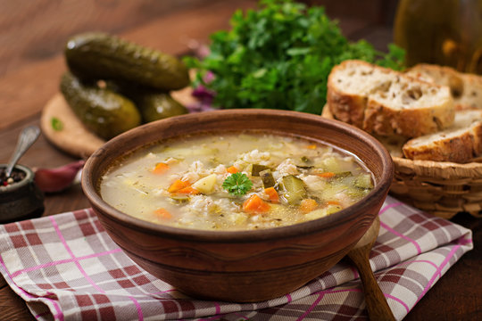 Soup with pickled cucumbers and pearl barley - rassolnik on a wooden background.
