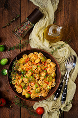 Vegetarian Vegetable pasta Rocchetti with brussels sprouts, tomato, eggplant and paprika in brown bowl on wooden table. Top view