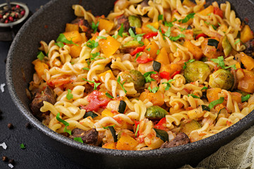 Fusilli vegetable paste with pumpkin, Brussels sprouts, paprika and liver pieces on a dark backgroundve