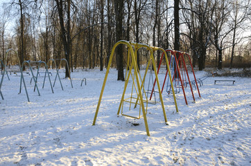 Swing at the deserted playground covered with snow in winter time