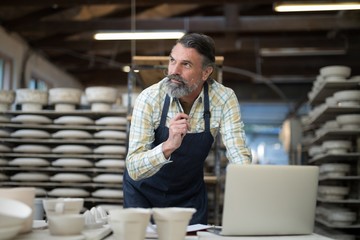 Thoughtful male potter working at worktop