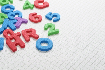 Naklejka premium Alphabet letters and numbers pile isolated on white checkered background