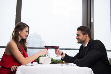 side view of couple clinking glasses of red wine while celebrating st valentine day in restaurant