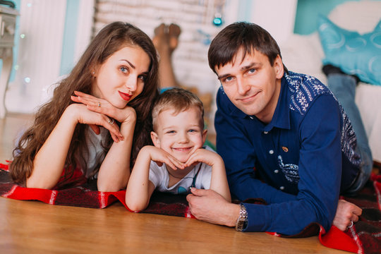 New Year's picture of happy family on background of Christmas decorations. Young parents with their son having fun and smiling on background of Christmas decorations