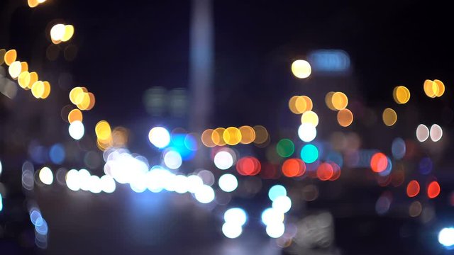 Defocused traffic lights at night. Colorful city bokeh. Cars out of focus.