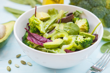 Green diet vegetable salad with peas, broccoli, avocado and pumpkin seeds.