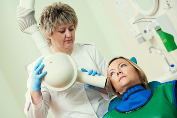 dentist operates dental intraoral x-ray unit for tooth image with patient