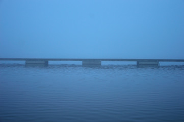 Molo nad jeziorem w zamglony poranek.